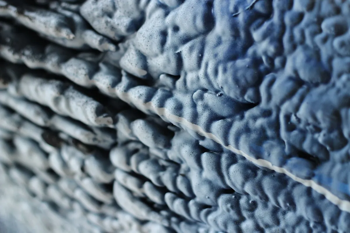 Cured spray foam insulation in close view — foam is the premium tier on this page: it air-seals as it insulates, and it is priced per board foot rather than by the bag.
