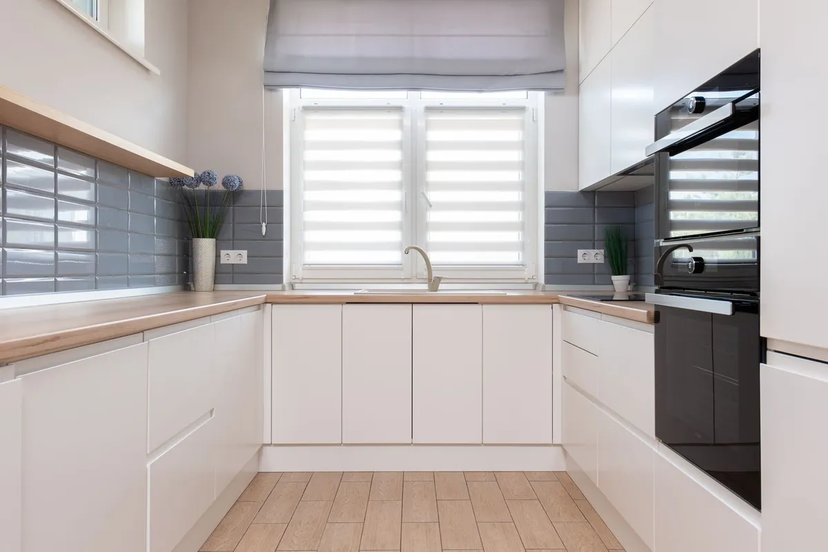 A U-shaped kitchen with the same gray tile carried along both walls — a backsplash is priced by the square foot of wall covered, so a second wall adds area to the same project rather than starting a new one.