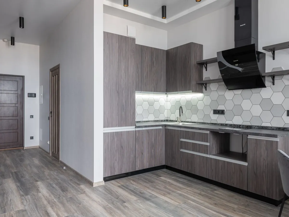 Kitchen with a hexagonal tile backsplash running the full length of the counter under a range hood