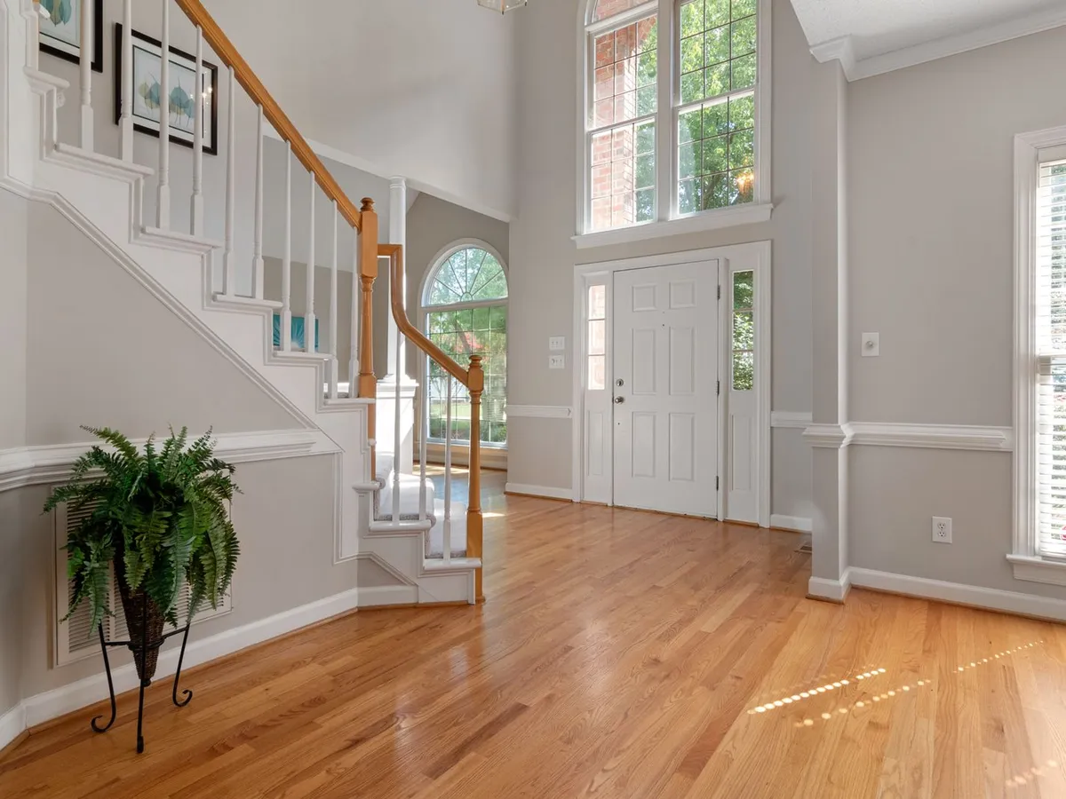 Entry hall with hardwood floors, a staircase and white baseboards along every wall