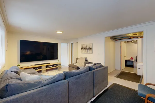 Finished basement living room with a large TV, comfortable sofa and recessed lighting