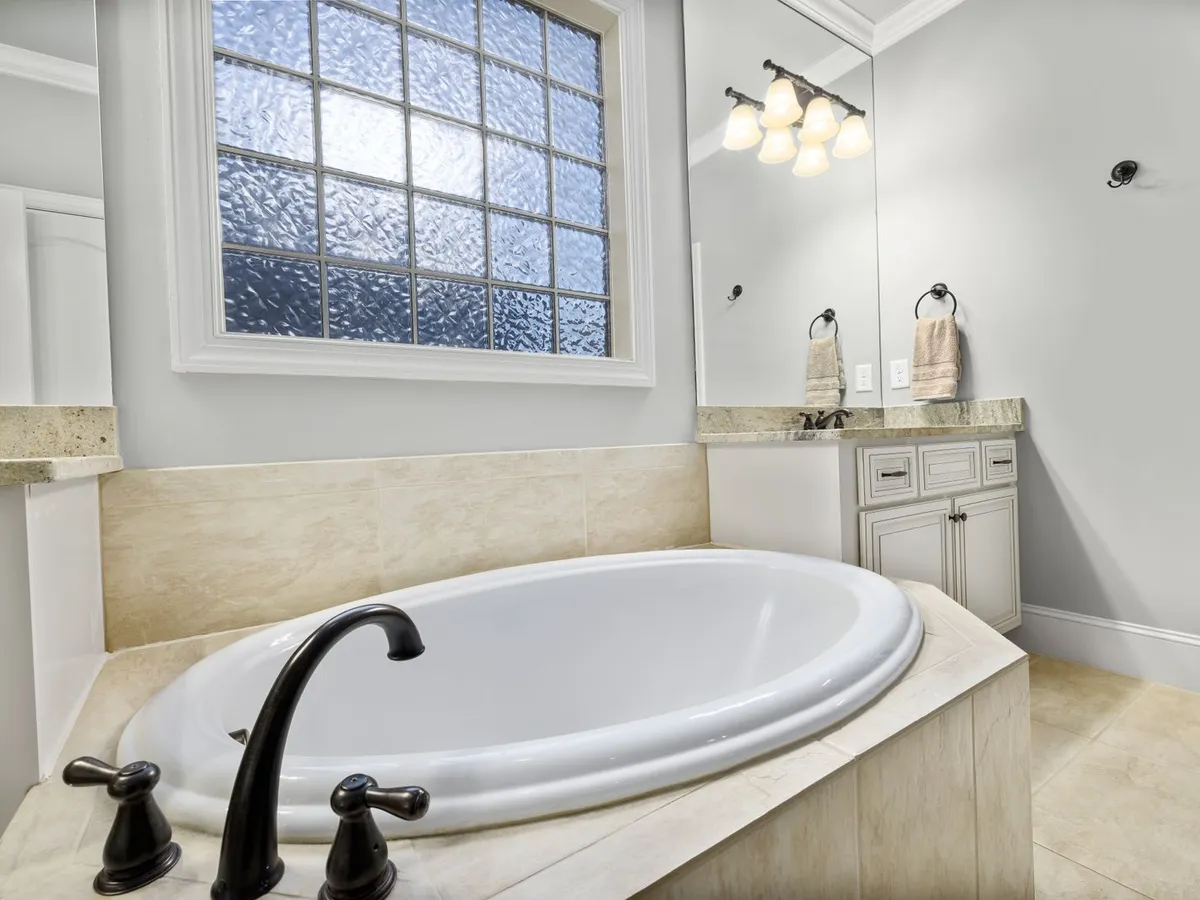 Oval soaking tub set into a tiled deck with a black filler faucet