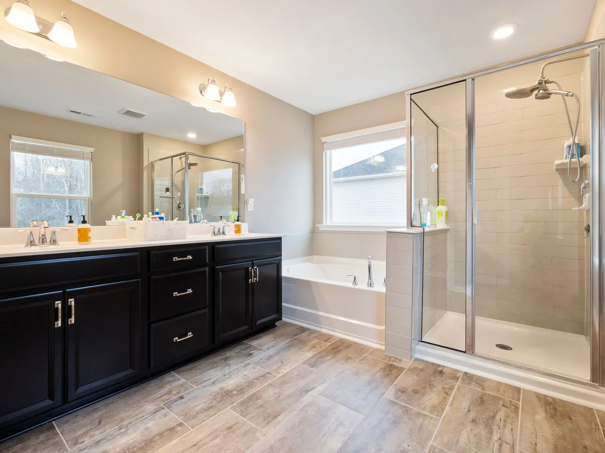 Finished bathroom with a glass-enclosed walk-in shower, double vanity and natural light