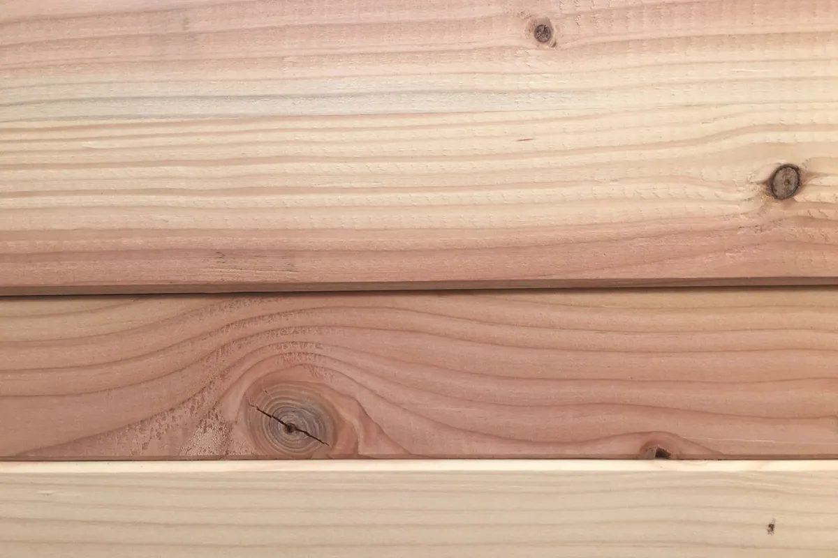 Wood planks in close view, showing grain and knots — species and grade are written into the surface like this, and they are the single biggest step between the tiers on this page.
