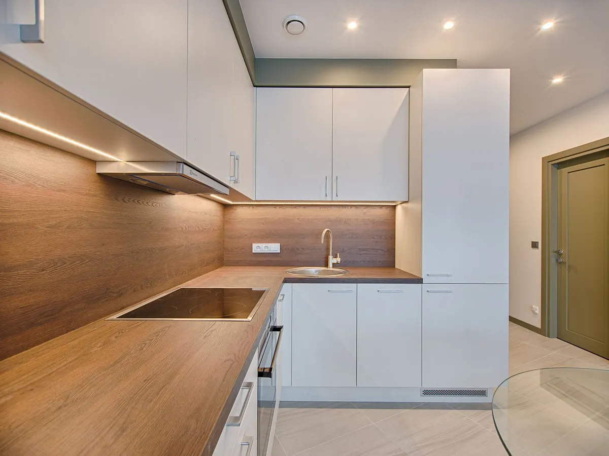 Kitchen with a wood countertop run, a cooktop cutout and white cabinets