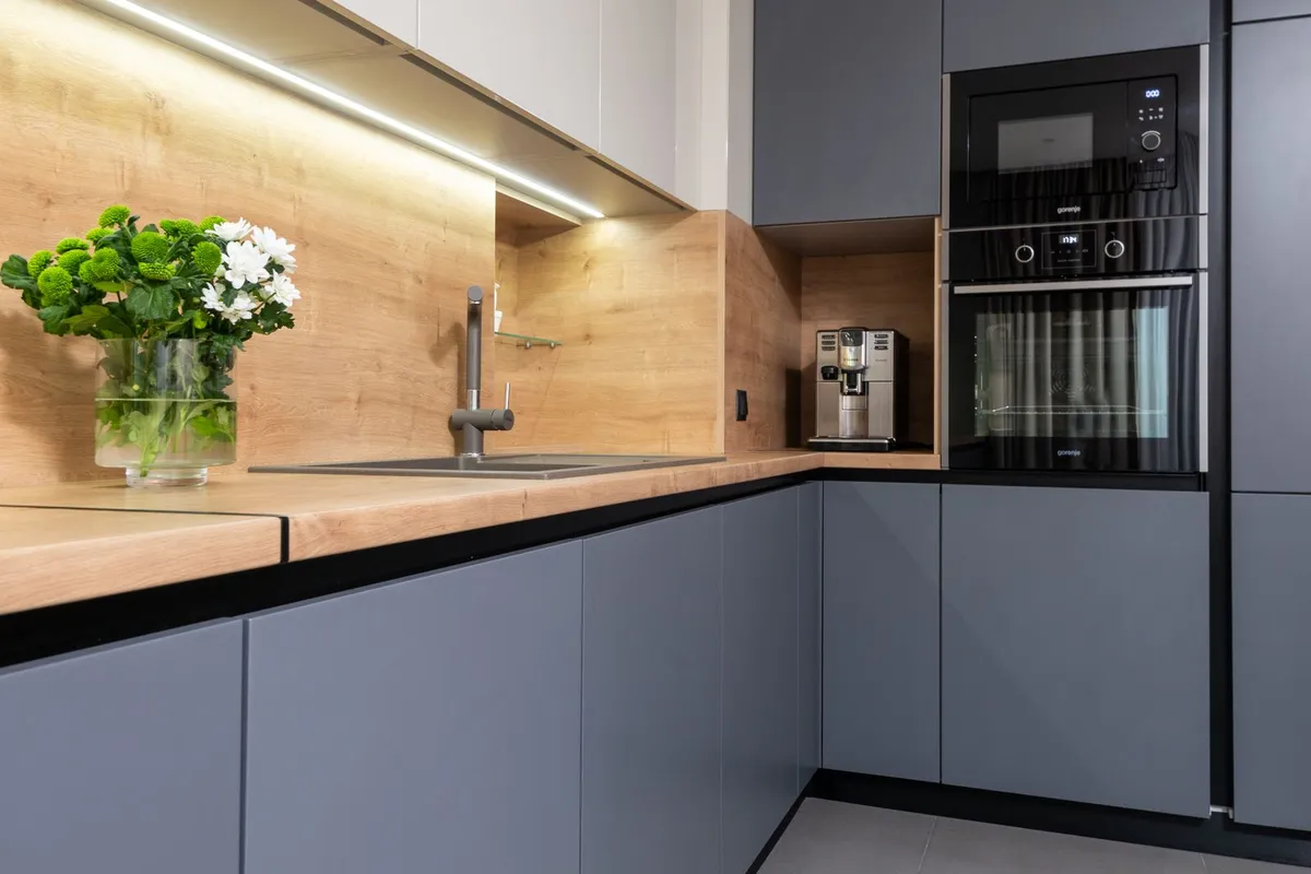Gray cabinet fronts seen at an angle in close view — door style and material class set the refacing price more than anything else: the same kitchen prices very differently in thermofoil, wood veneer and solid wood.