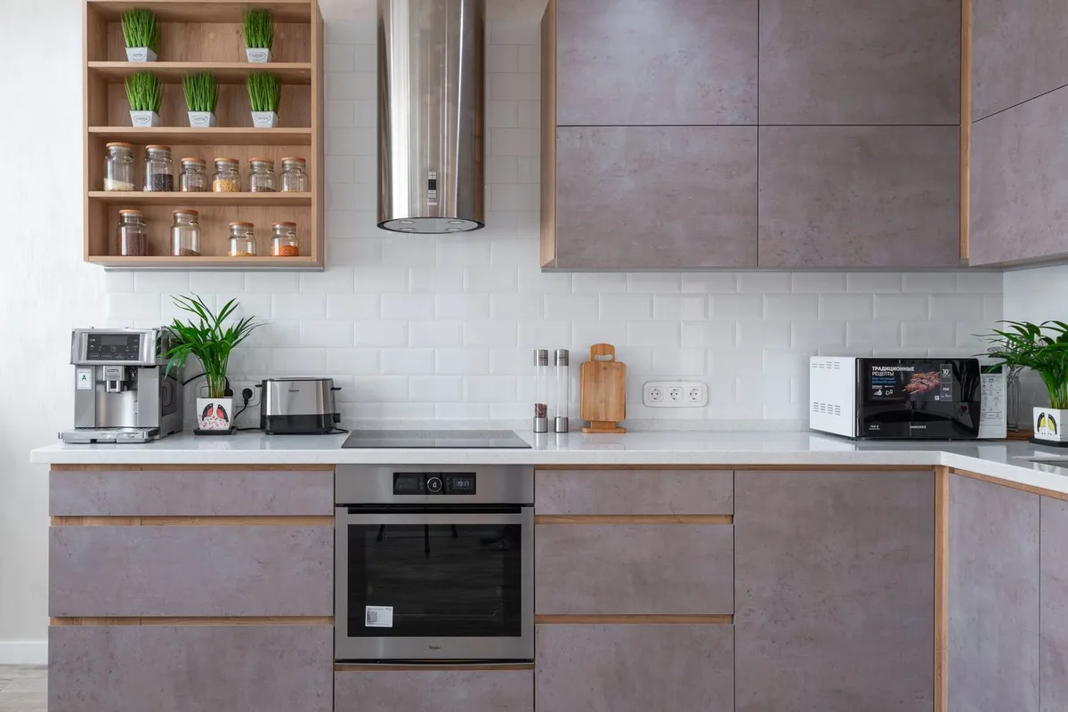 A modern kitchen with stone-look flat cabinet fronts — this is the refaced result: new doors, drawer fronts and veneer over the existing boxes, which is why doors, fronts and veneer are 40–55% of a refacing budget.