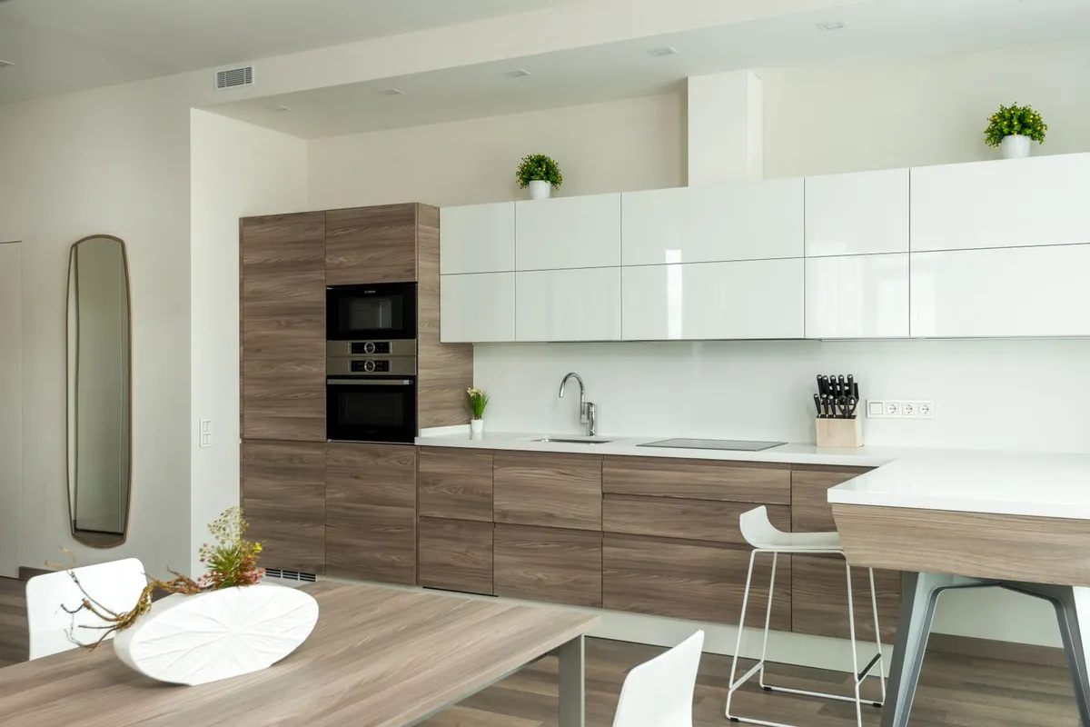 A long kitchen run with smooth light counters and wood fronts — finish is the concrete ladder: basic, coloured, then stained or polished, each step priced per square foot in the guides.