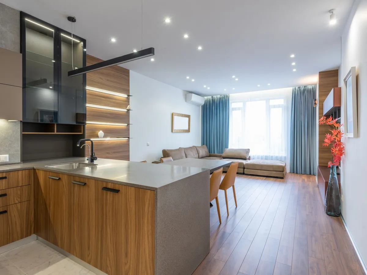 Kitchen island with a matte grey counter and waterfall end, wood cabinets alongside
