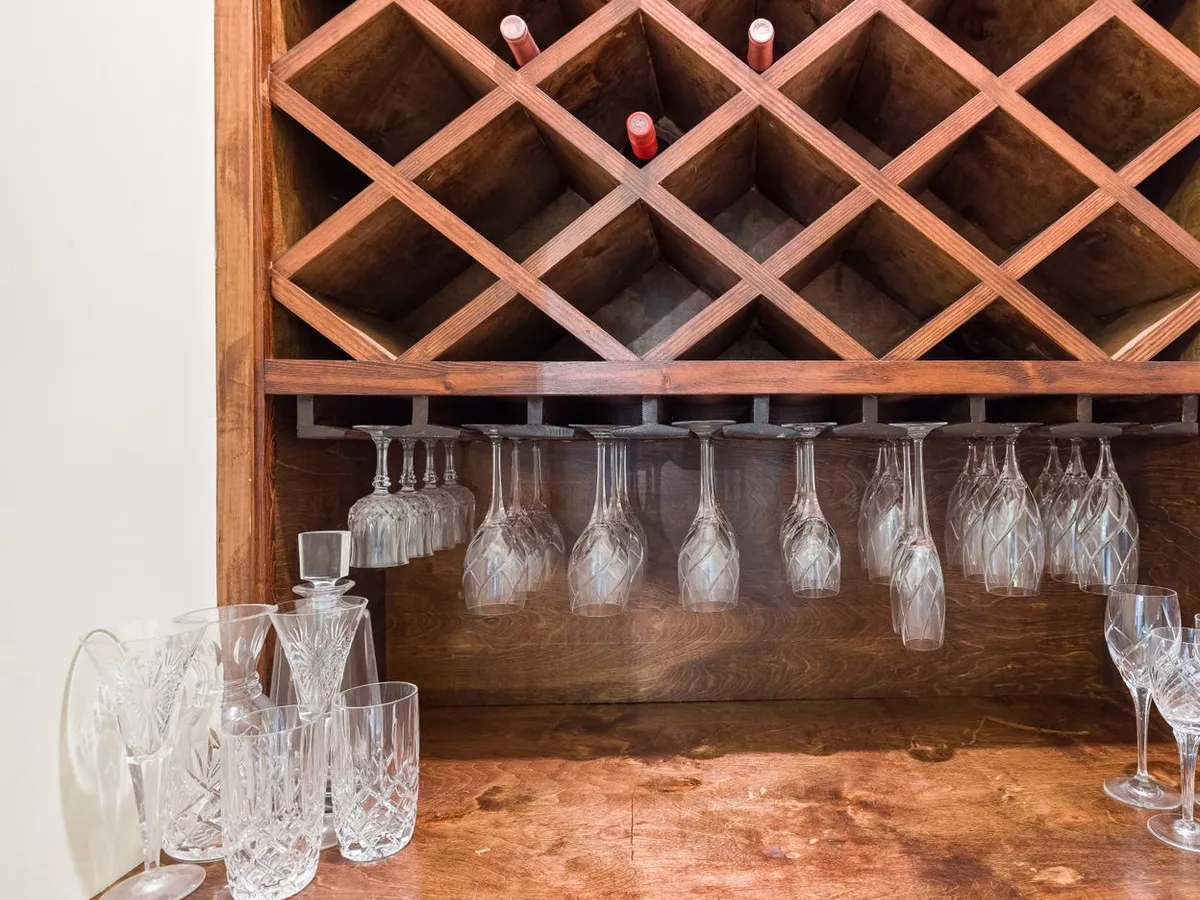 Home bar with a worn copper-brown metal counter, wine rack and hanging crystal glasses