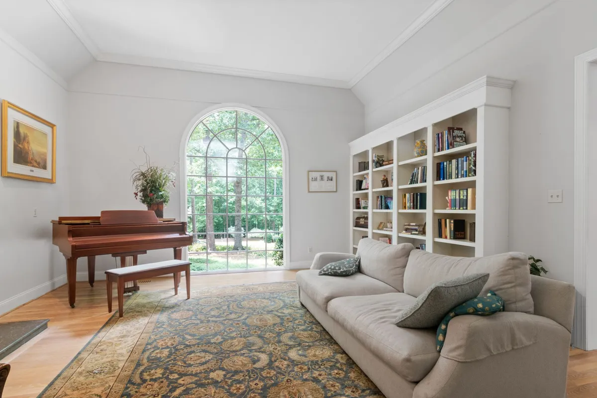 A living room with a grand piano standing on a light plank floor — heavy furniture is cork's known weakness: it dents under point loads, so felt pads under legs and feet are part of owning this floor, not an accessory.