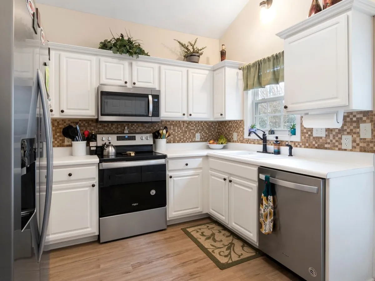 White kitchen with a stainless steel dishwasher beside the sink under the window