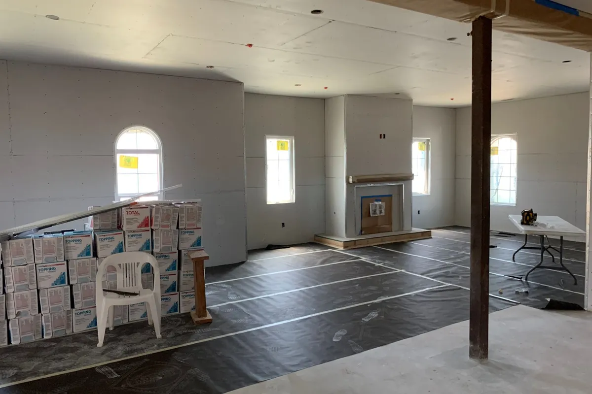 A drywalled room with stacks of joint compound boxes waiting for the finishing coats — hanging is the fast stage; taping, mudding and sanding are the labour that makes up 65–75% of a typical drywall budget.