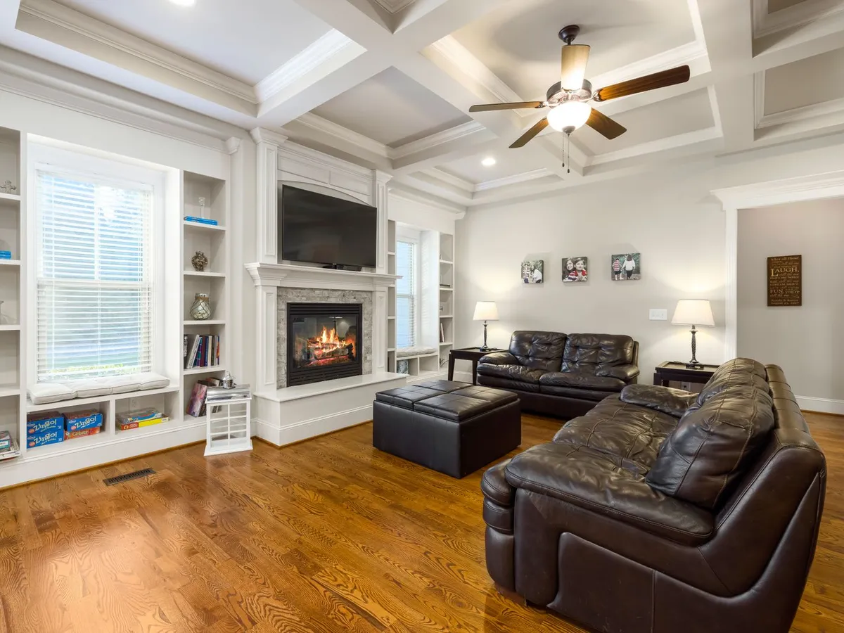 Living room with a rich medium-tone wood plank floor, a fireplace and leather sofas