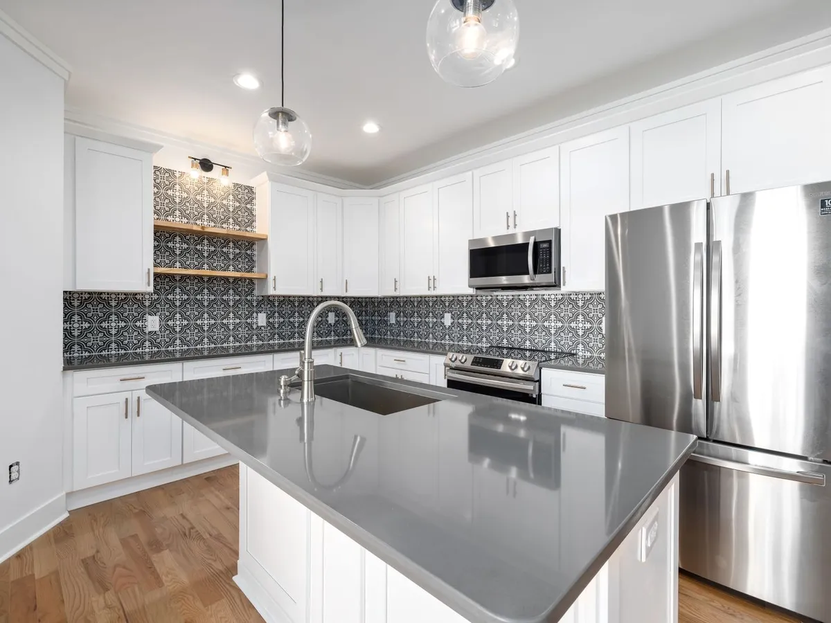 White kitchen with a large island topped by a smooth glossy solid-grey counter and an undermount sink