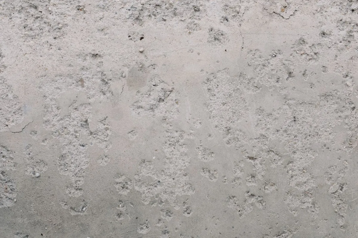A pitted, weathered concrete surface in close view — epoxy bonds to the slab it is given, so grinding, crack repair and moisture checks on a surface like this happen before any resin is opened.