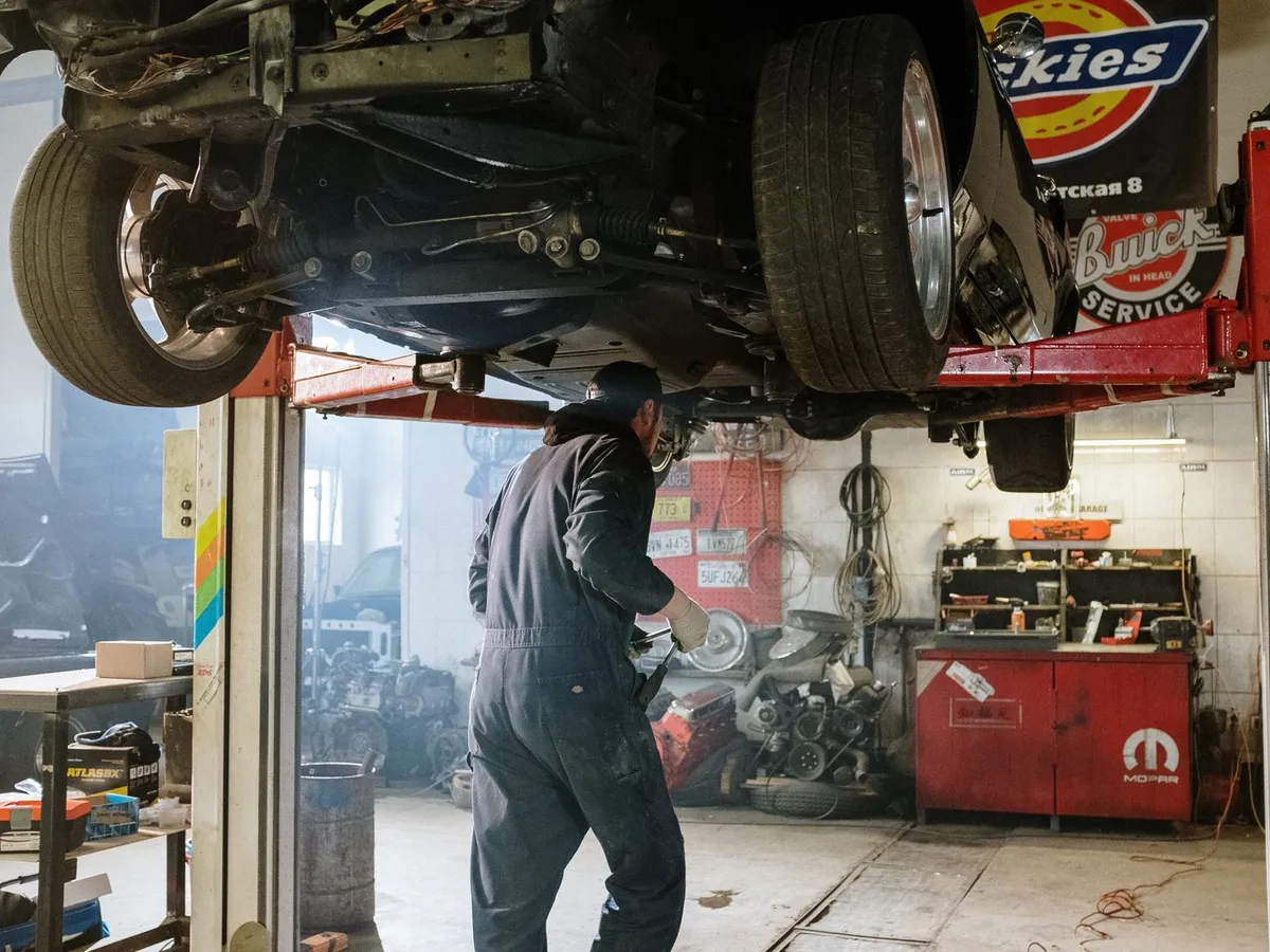 Auto workshop with a car raised on a lift above a worn concrete floor