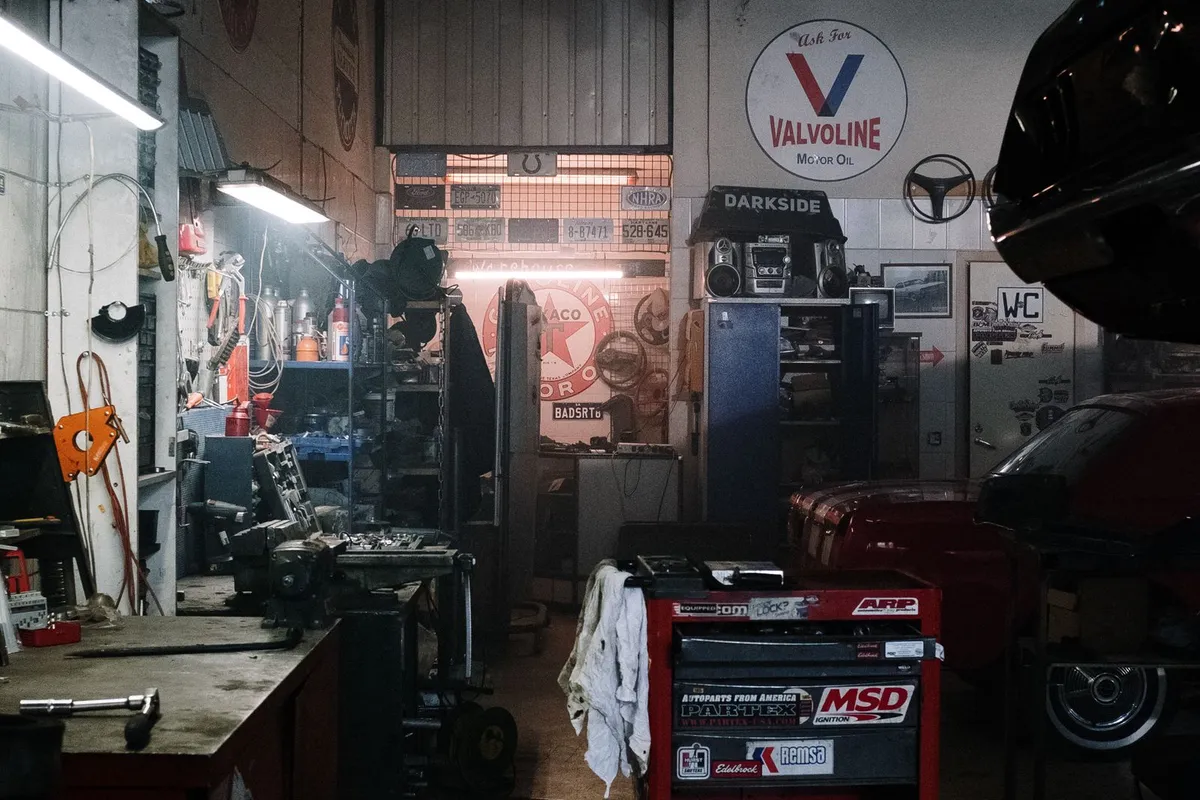 A working workshop interior with its concrete floor in view — epoxy is priced by the square foot of slab it coats, and a floor that has carried oil, tyres and lifts like this one is exactly the preparation case the prep line in the breakdown pays for.