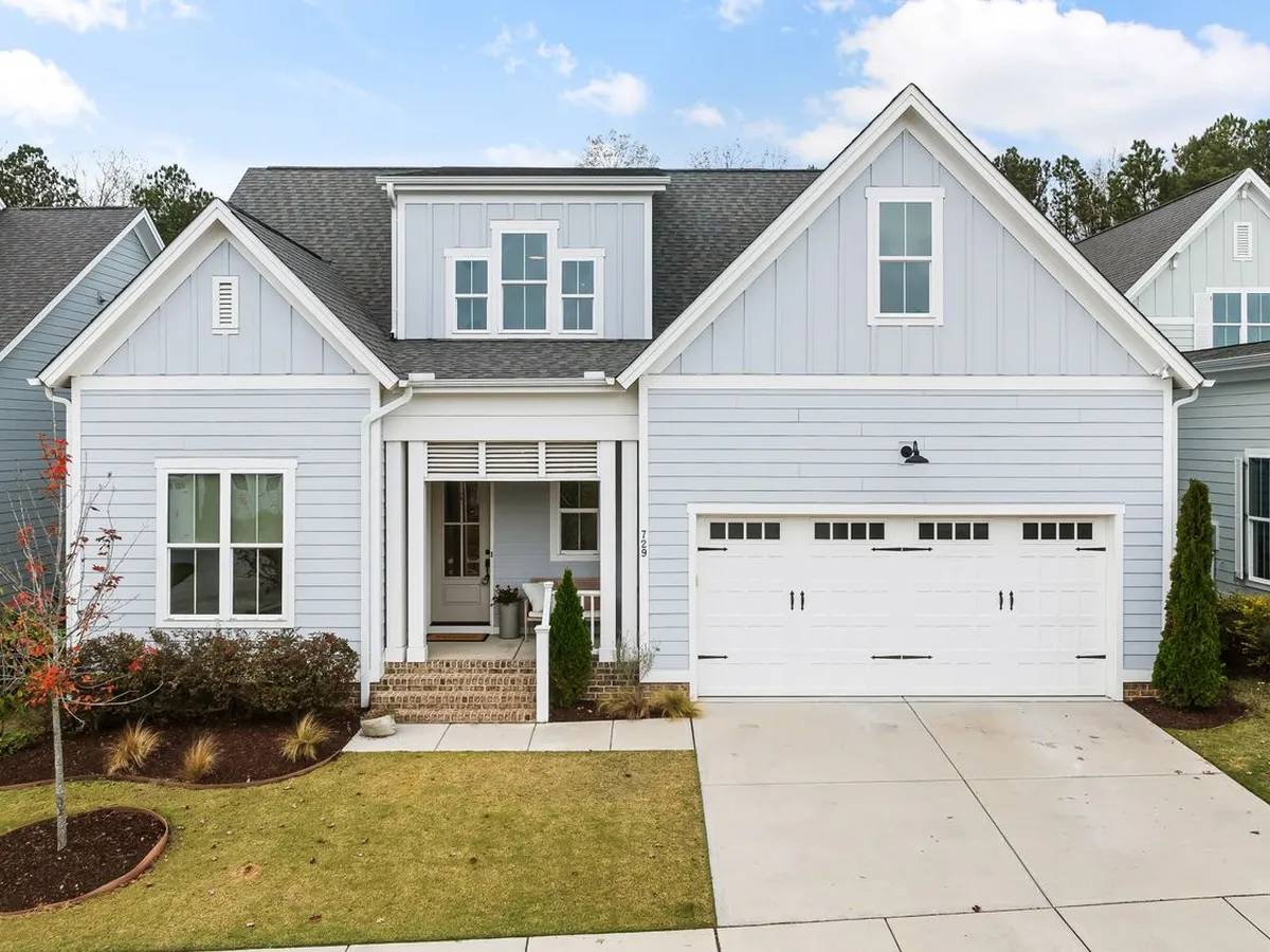 Light-blue house with a white double garage door and a concrete driveway