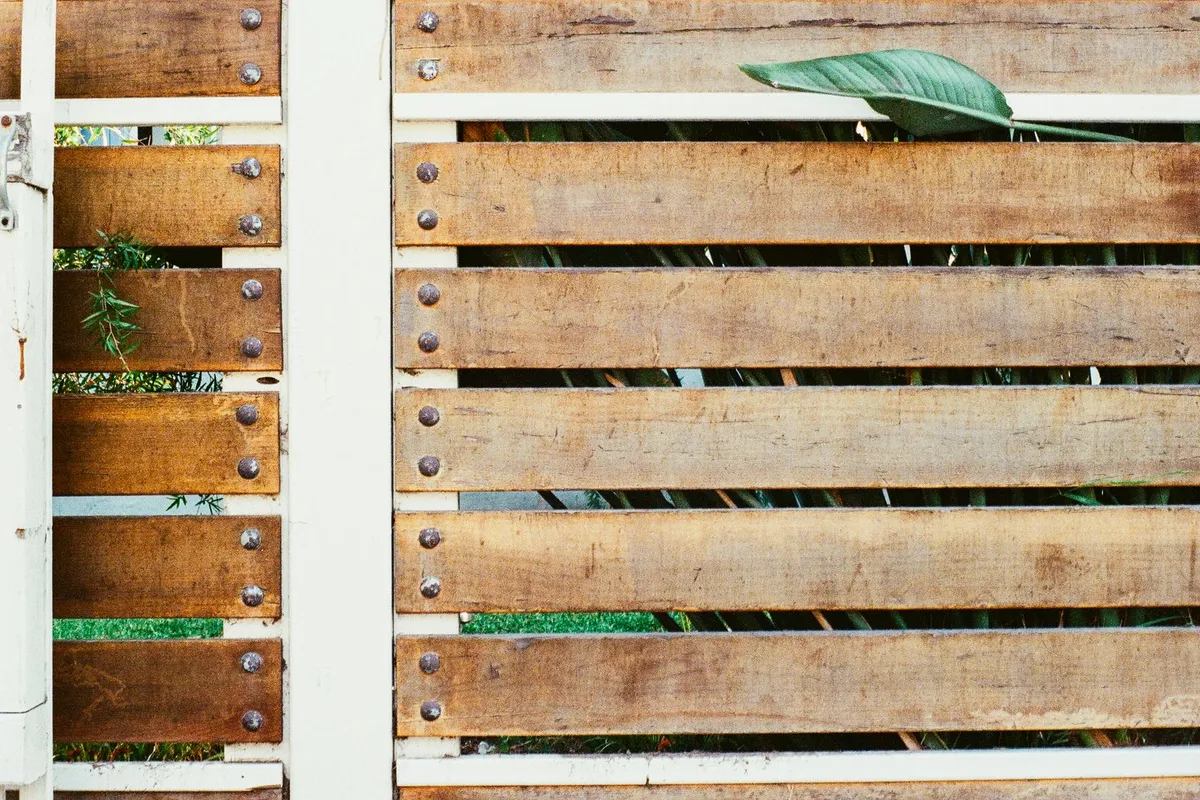 A horizontal-slat wood gate with bolted hardware in close view — gates and hardware are 5–10% of a fence budget, and a wide double or driveway gate costs considerably more than a standard walk gate.