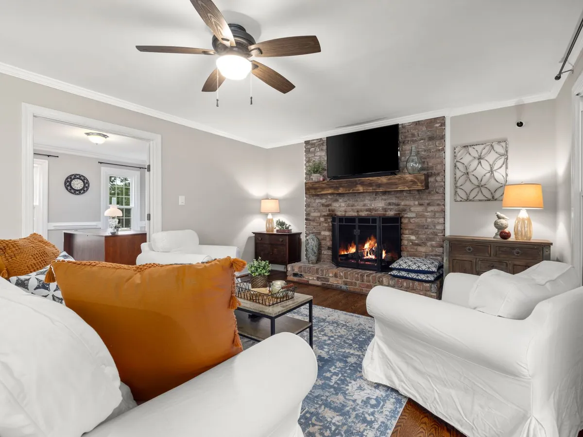 Living room with a brick fireplace, a fire burning behind glass doors and a wood mantel