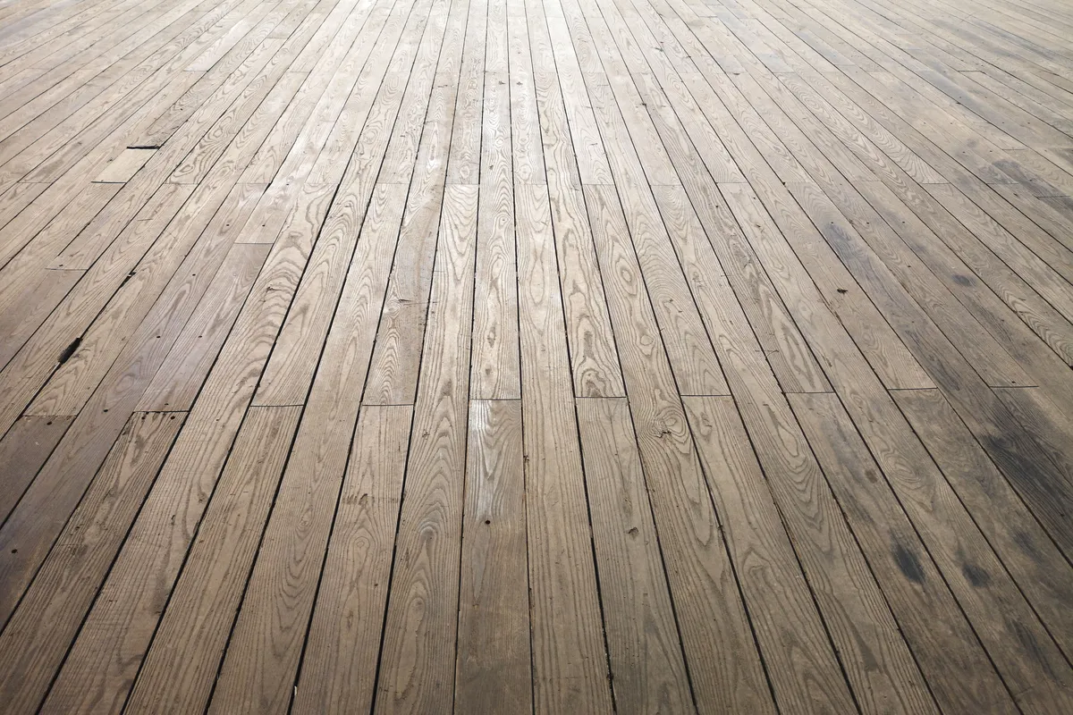 A close view of wood plank flooring showing grain and plank joints — plank width, grade and finish decide where a material lands inside its price band.