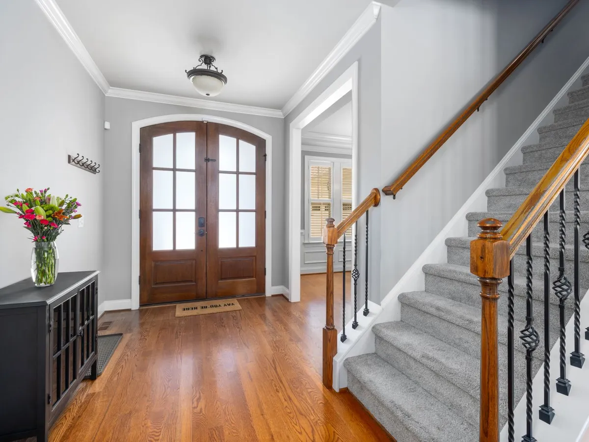 Foyer with dark wood double French doors with divided glass lites beside a staircase