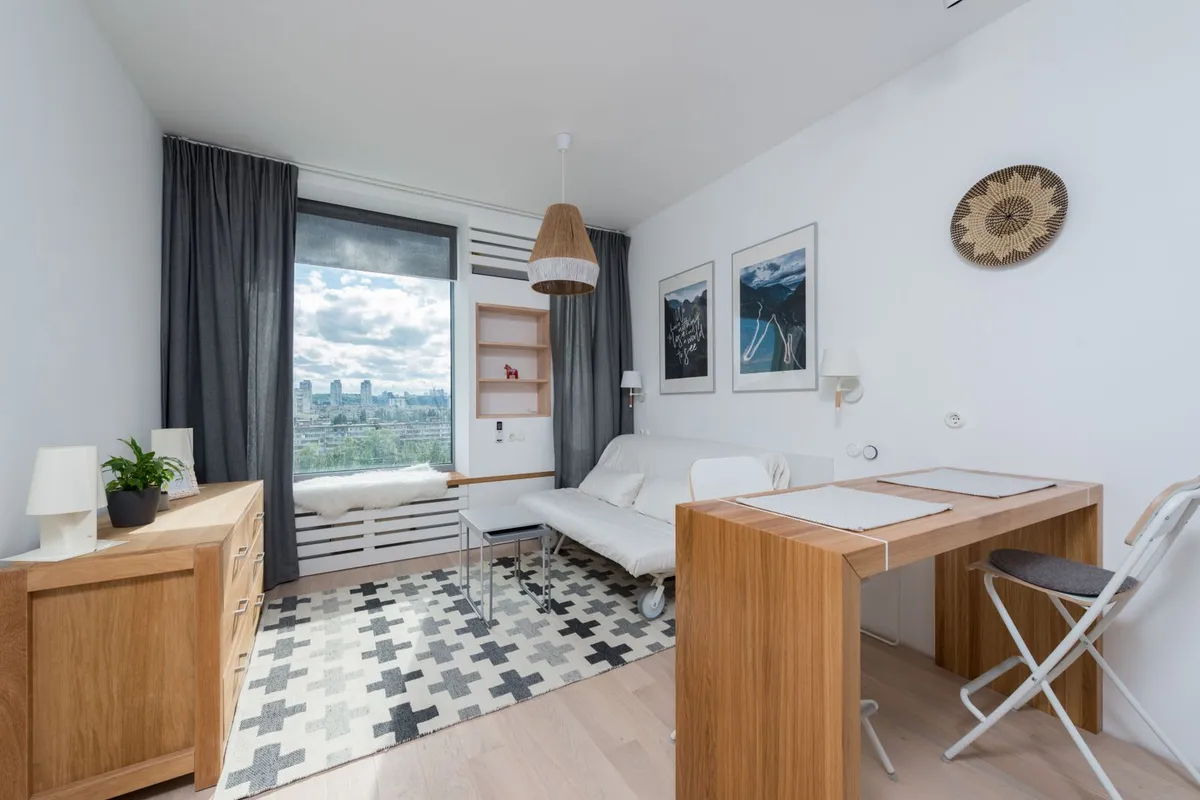 A small studio living area with a sofa bed and a desk — the finished living space a conversion buys; a basic no-plumbing conversion is the entry tier, before a bathroom or kitchen is added.