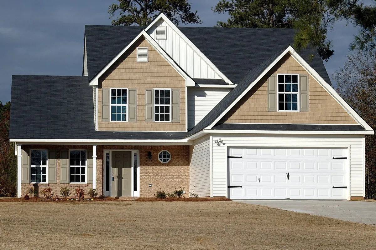 A house with a white double garage door with carriage-style hardware — a double door carries more material, heavier springs and longer fitting time than a single.
