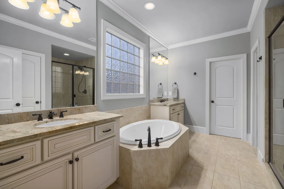 A bathroom double vanity topped with a beige speckled stone counter — the slab and its fabrication are 50–65% of a granite budget, and a vanity run shows the same stone priced by the same square foot as a kitchen.