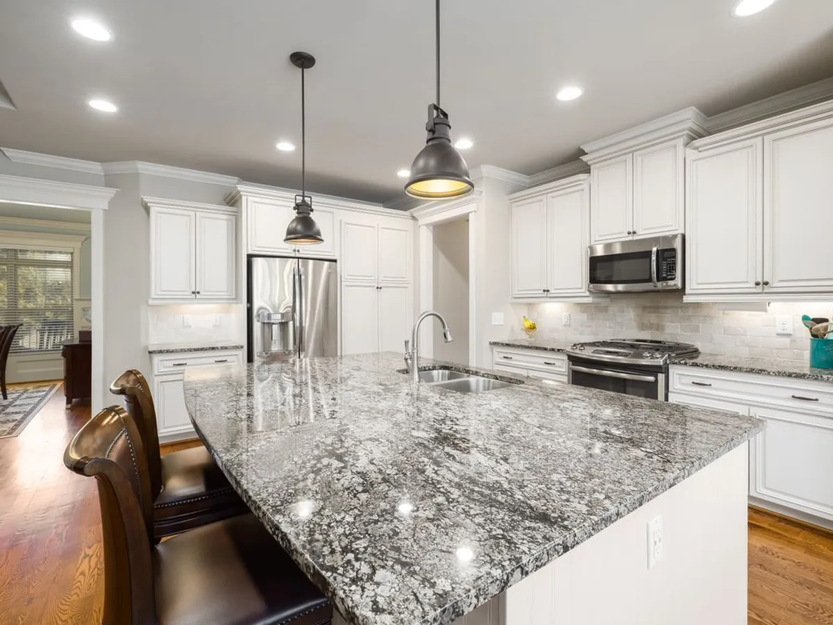 Kitchen with white cabinets and a large speckled granite island countertop