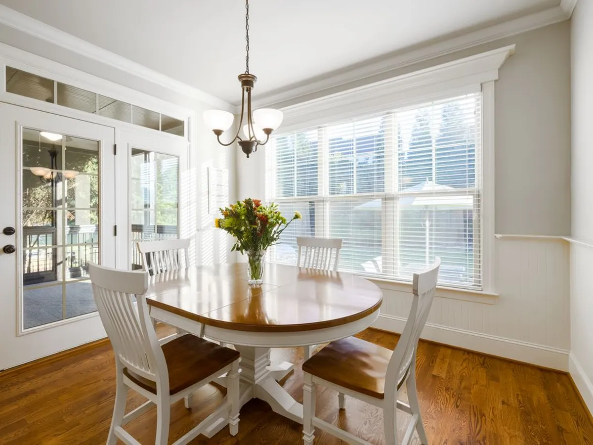 Dining room with a rich wood floor, white chairs and French doors