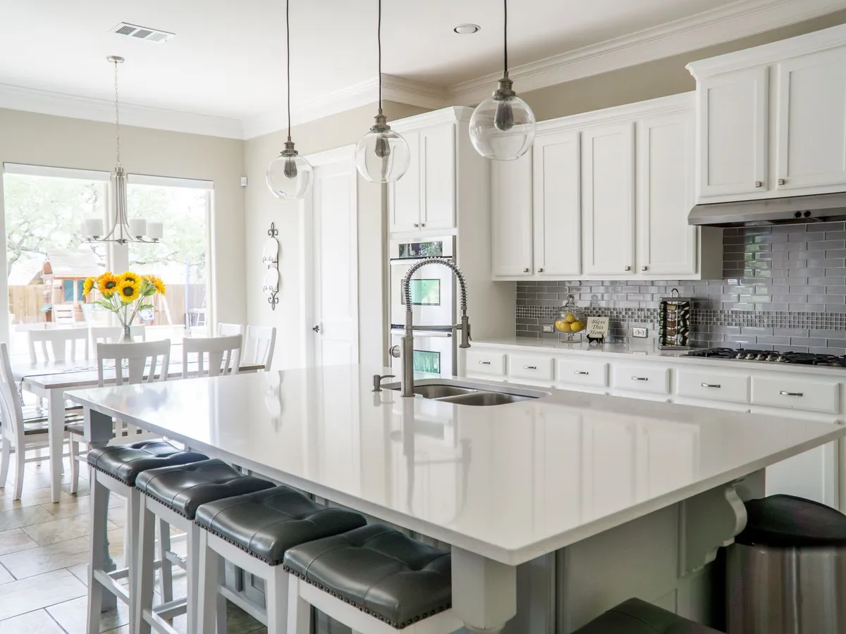 Finished kitchen with white cabinets, a large island and pendant lighting