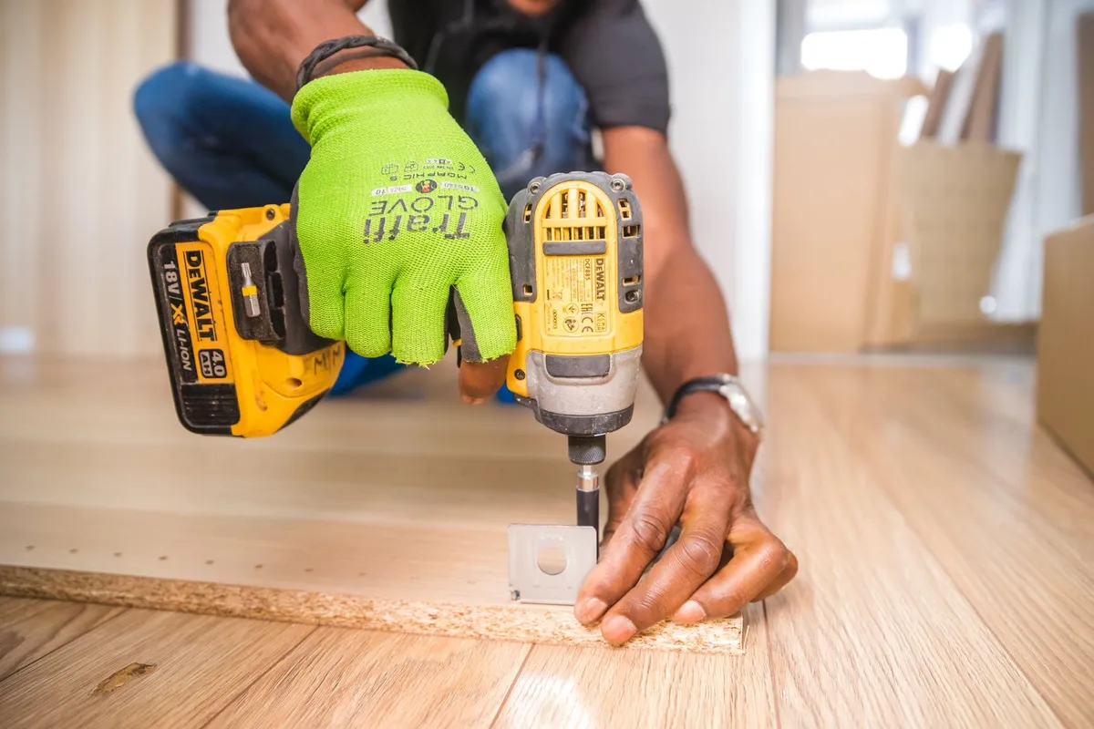 An installer assembling a cabinet panel with an impact driver — installation labor is 15–25% of a cabinet budget, and leveling and fitting work like this is what that share buys.
