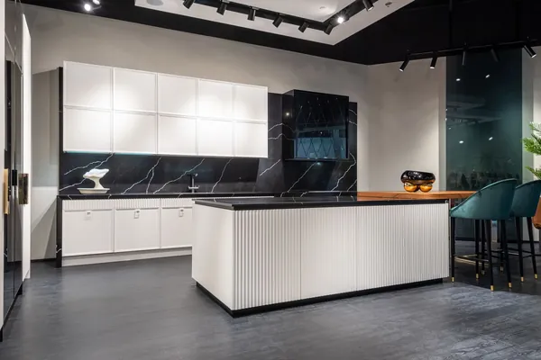 Finished modern kitchen with white cabinets, black countertops and a central island