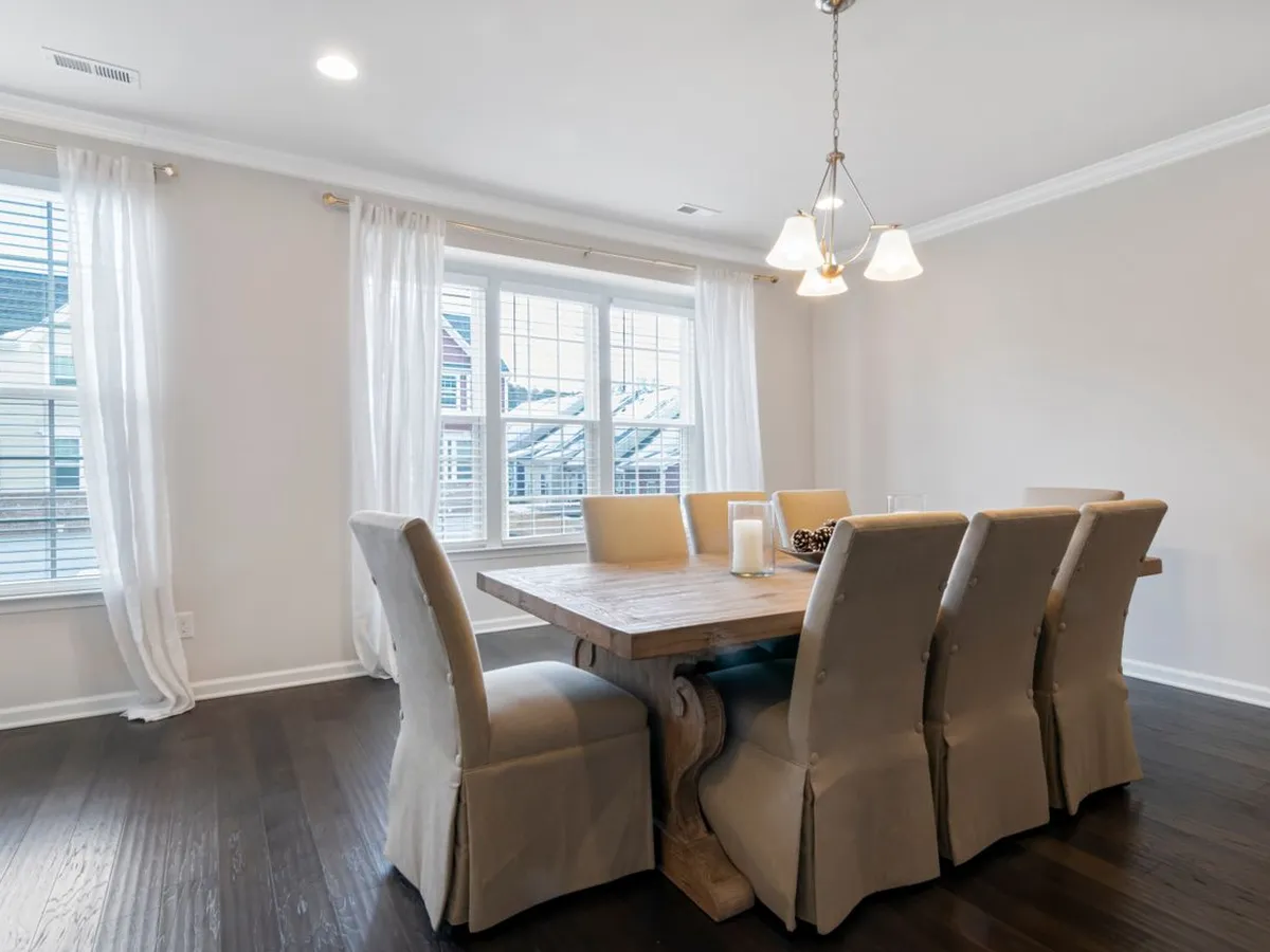 Dining room with a three-shade chandelier over a wood table and a recessed ceiling light