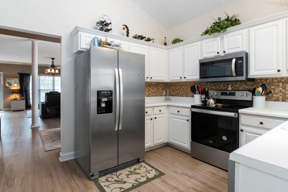 A white kitchen with light counters and a mosaic tile splashback — limestone's soft, light palette is the look priced on this page, and its annual sealing is the upkeep that comes with it.