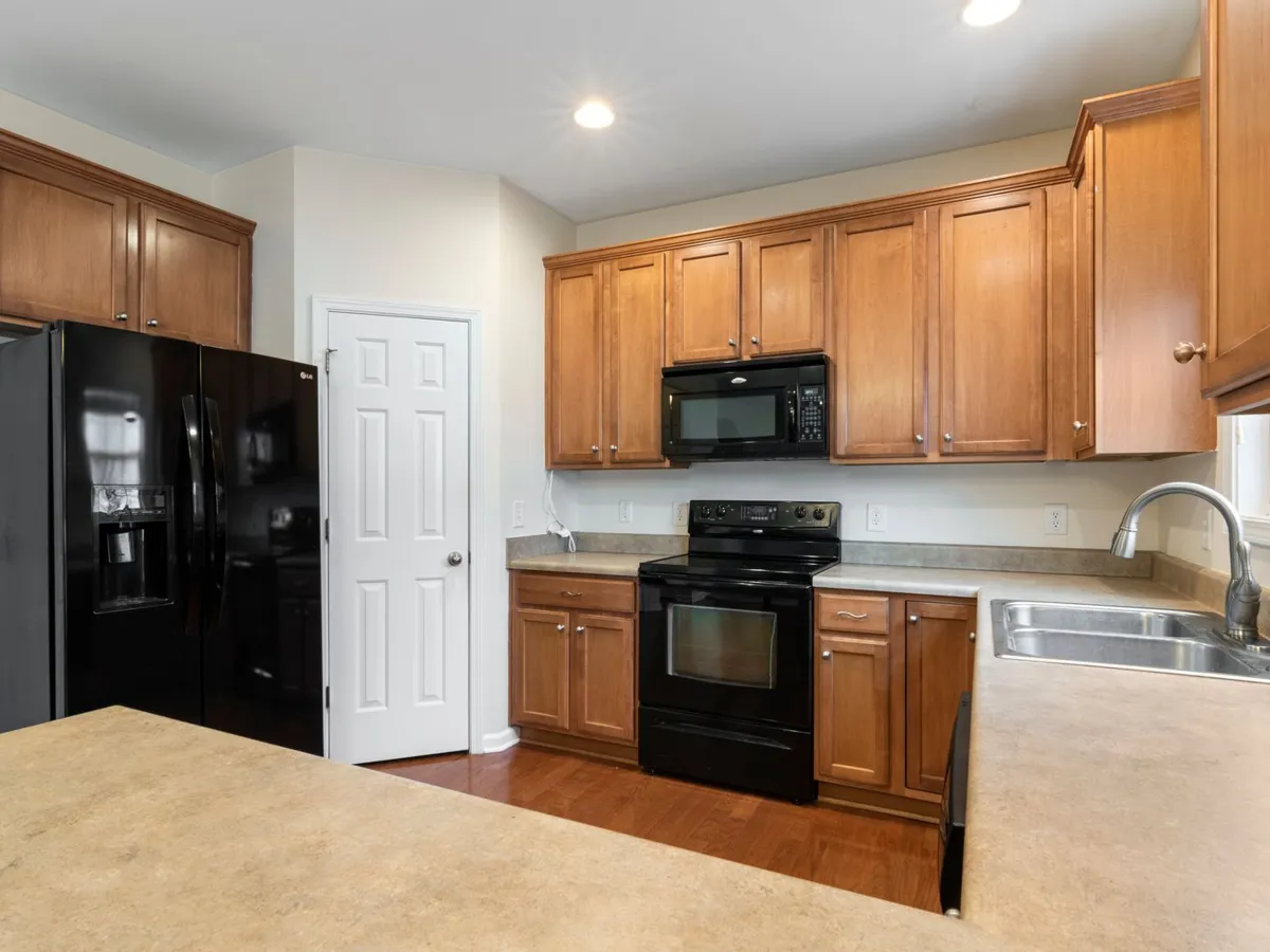 Kitchen with wood cabinets and a light beige stone-look counter in the foreground