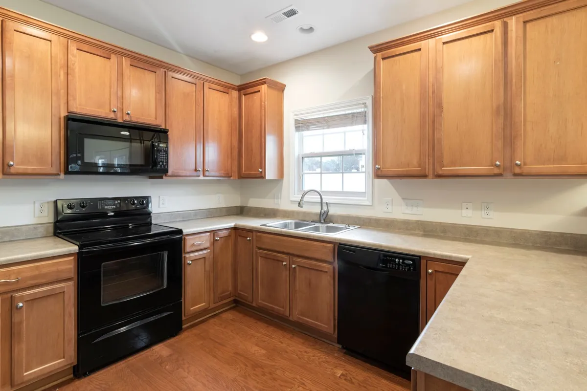 The same light counters running under a window with the sink cut in — slab quality and finish decide most of a limestone budget, and the sink cutout you can see here is part of the fabrication line. Captions describe the visible light stone only; the pictured counters are not certified as limestone.