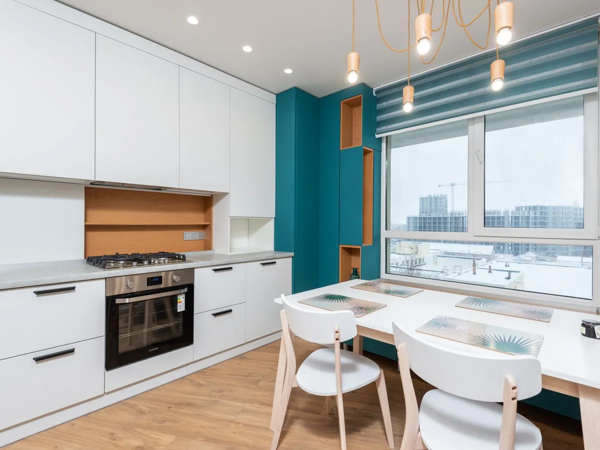 Kitchen with white cabinets, teal walls and a light wood-look floor