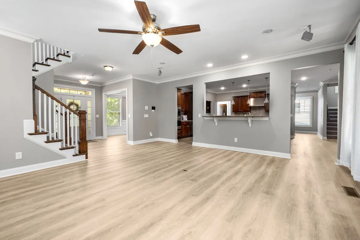 An empty living room on a light plank floor — flooring is priced on the full measured floor area, and linoleum's material is 45–60% of an installed budget, so the format chosen for a run like this sets most of the project total. Captions on this page describe the visible floors; the pictured floors are not certified as linoleum.