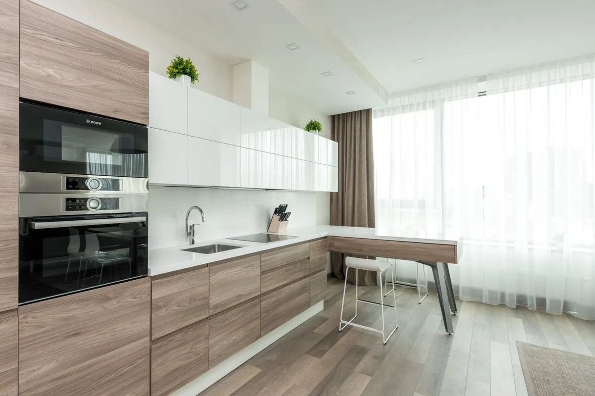 A kitchen with a gray wood-look plank floor — kitchens are the room LVP is built for: the plank is waterproof, which is why it, and not laminate, is the guides' recommendation wherever water is a daily fact.