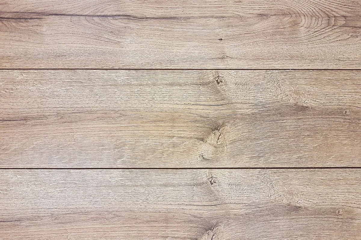 Oak-look vinyl planks in close view — the wear layer on the surface is the part you walk on: plank material is 45–60% of an LVP budget, and wear-layer thickness is the honest difference between the budget and premium tiers.