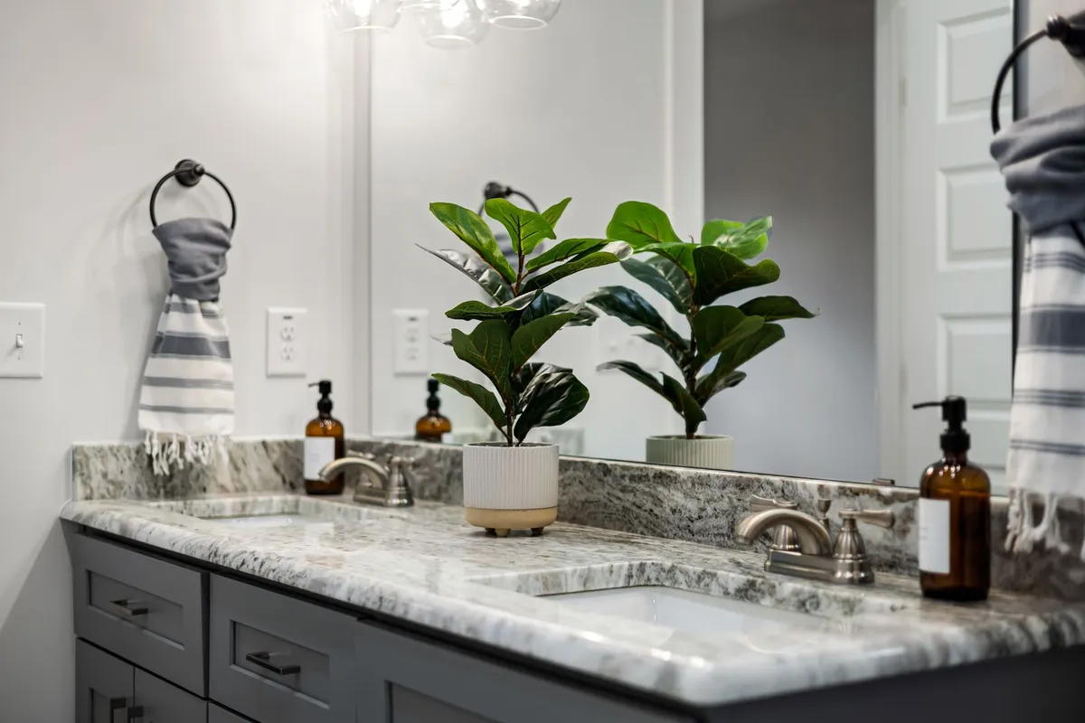 A veined stone vanity counter in close view — the slab and its fabrication are 55–70% of a marble counter budget, and the sink cutouts and edge profile you can see here are part of that fabrication work, priced in the shop before the stone reaches the house.