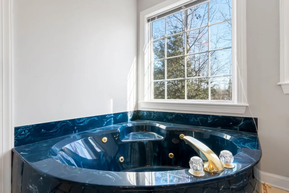 A deep blue swirled stone tub surround in the same bathroom as the hero vanity — translucent, dramatically veined stone is the look priced on this page, and its fragility in handling is why installation is specialist work.