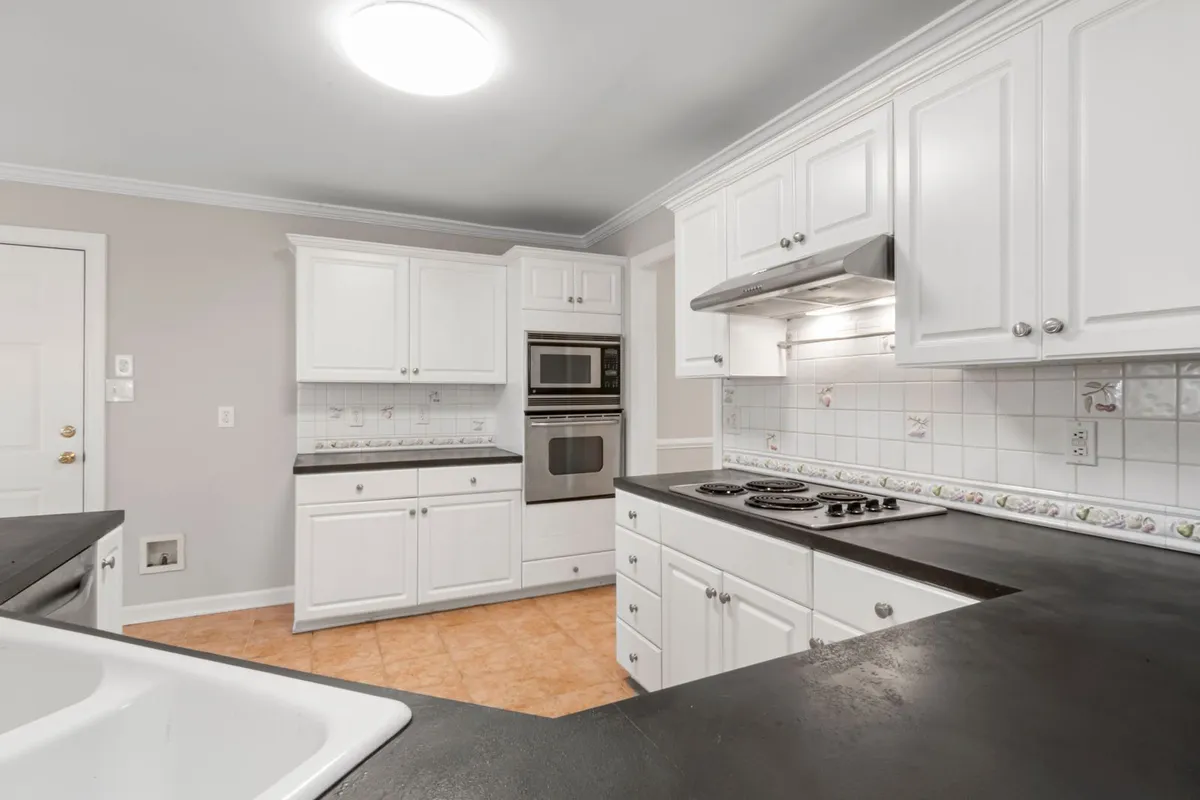 A kitchen run with dark stone counters — onyx slab and fabrication are 60–75% of a standard budget, and a long run like this is priced by the square foot of slab, seams included. Captions describe the visible stone only; the pictured counters are not certified as onyx.
