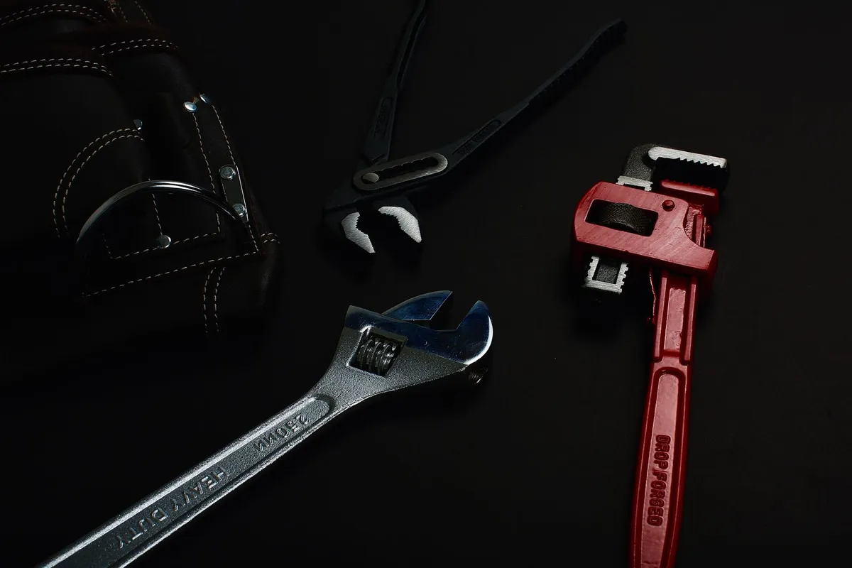 A plumber's pipe wrench, adjustable wrench and pliers laid out before work — a repipe is licensed, permitted work in most places, and labor runs 55–70% of the typical total.