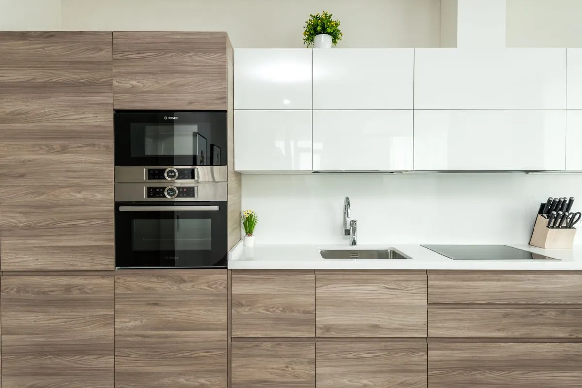A white counter run seen straight on, sink and induction cooktop set flush — quartz is non-porous and never needs sealing, which is part of what its per-square-foot price buys over natural stone.