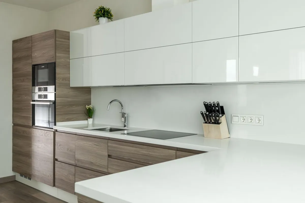 A glossy white counter run with its sink and cooktop cut into it — cutouts run $150–$300 each in the guides, and the slab and its fabrication are 55–70% of a quartz budget, so the layout you cut is the layout you pay for.