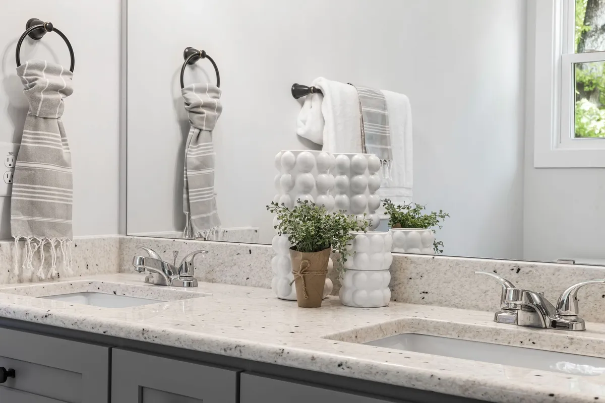 A bathroom double vanity topped with a light speckled stone counter — vanity tops are priced by the same slab-plus-fabrication maths as a kitchen run, with each sink cutout counted in the fabrication line.